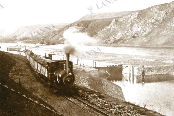 Projíždějící lokomotiva 6 podél zdymadla v Klecanech 19.1.1899. BAUER, Zdeněk. Stavební stroje firmy Lanna, 2005.